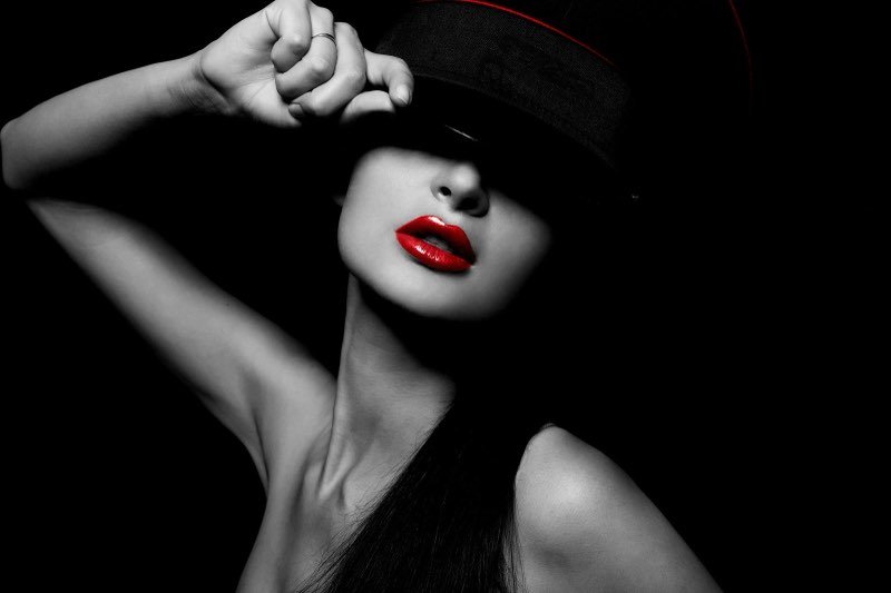 Retrato em preto e branco com boné e batom vermelho em destaque